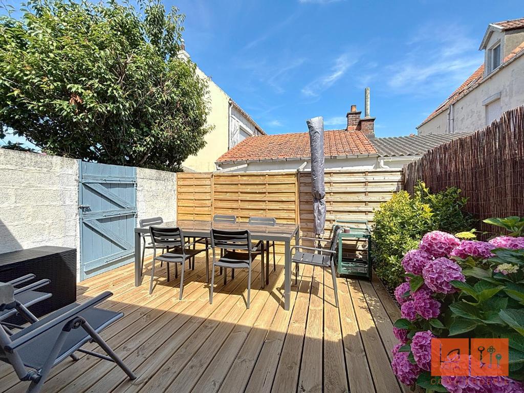 a patio with a table and chairs on a wooden deck at Au Gré de la Mer in Wimille