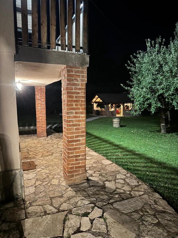 Un pilar de ladrillo junto a una casa por la noche. en Rancbl, en Banja Luka