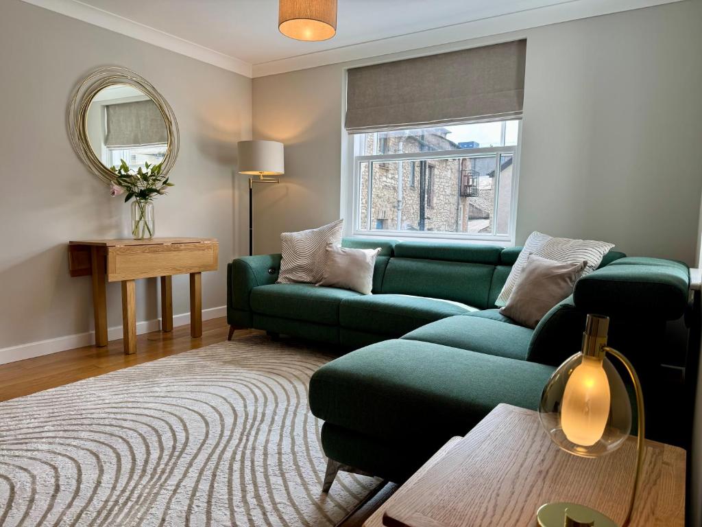 a living room with a green couch and a table at Rawes Cottage Kendal in Kendal