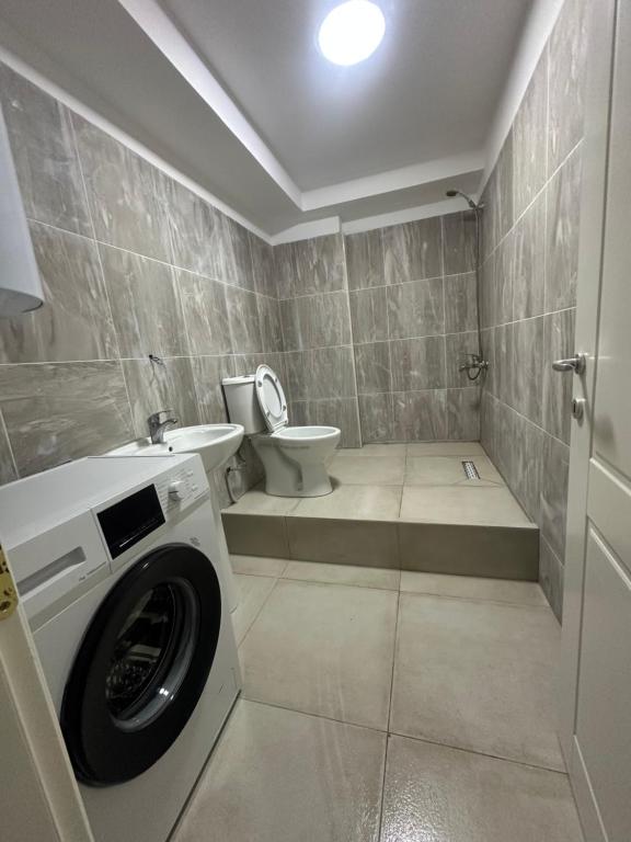 a bathroom with a washing machine and a toilet at Lejdon Daily Apartments Shengjin in Shëngjin