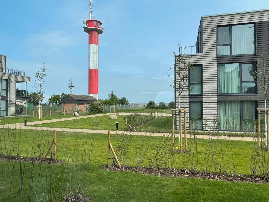 un phare avec un phare en arrière-plan dans l'établissement BeltBlick 14- Küstenleuchten - Moderne Ferienwohnung direkt am Strand mit Sauna und Garten!, à Fehmarn