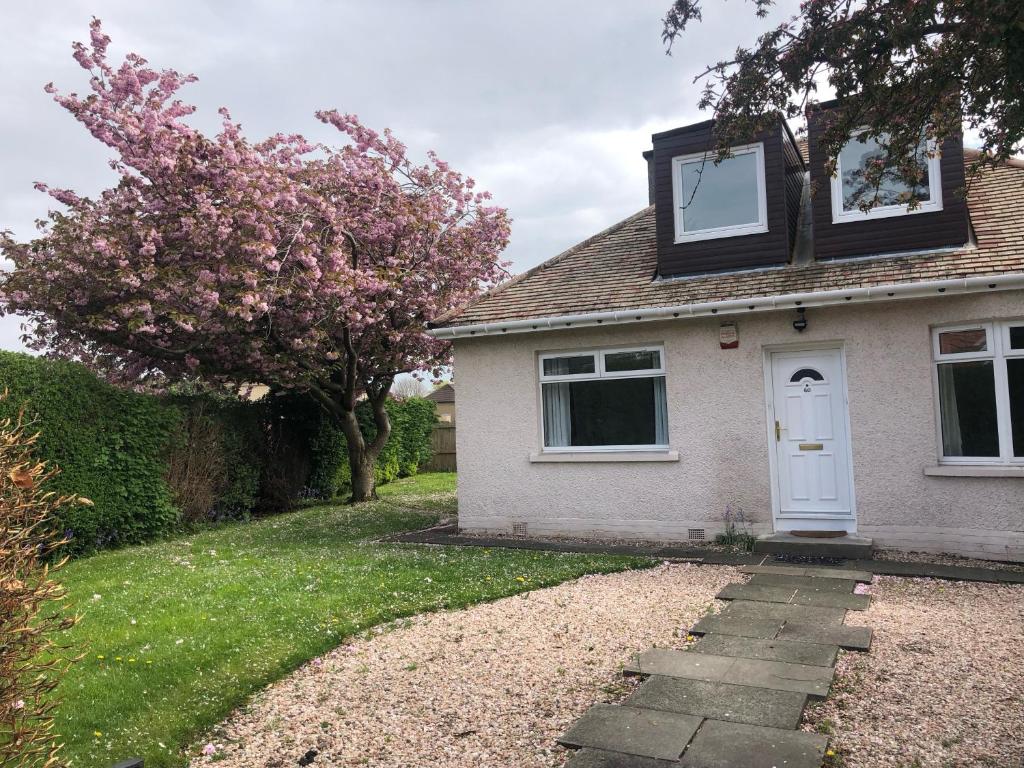 a white house with a white door and a tree at Stag's View Lodge in Edinburgh