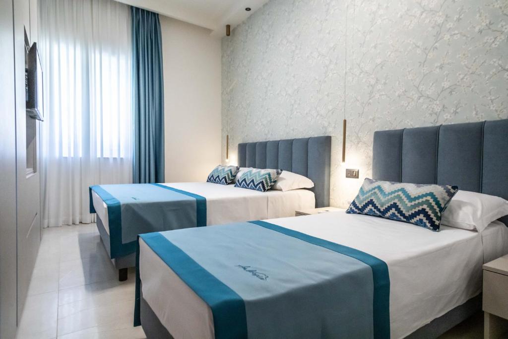 a hotel room with two beds and a window at Ambrosia Room & Apartment in Rossano