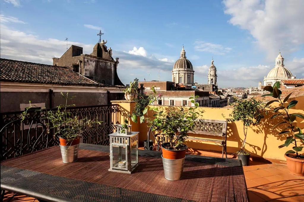 a balcony with potted plants and a view of a city at Charming Rooftop Flat in City Center in Catania