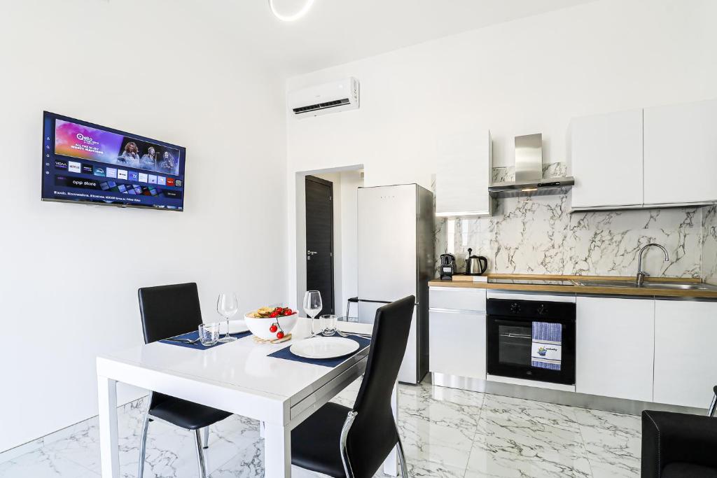 a white kitchen with a white table and chairs at Nettuno80 3 by Casa di Marco AP33 in Lido Conchiglie