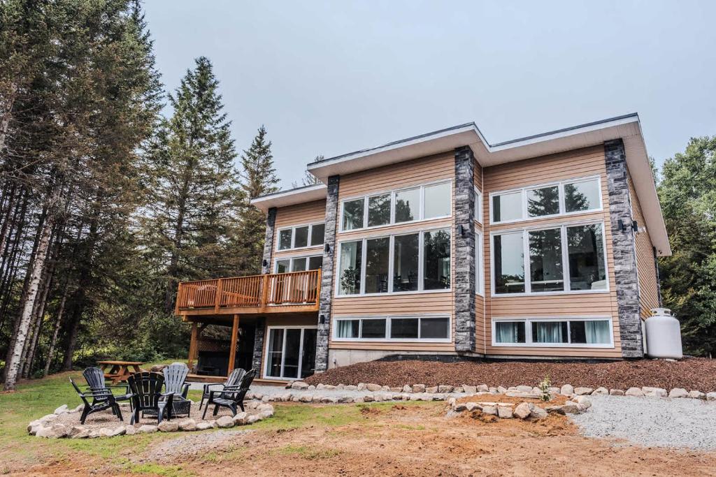 a large house with black chairs in front of it at Modern Waterfront Cottage on the Rouge River & Spa in Rivière-Rouge