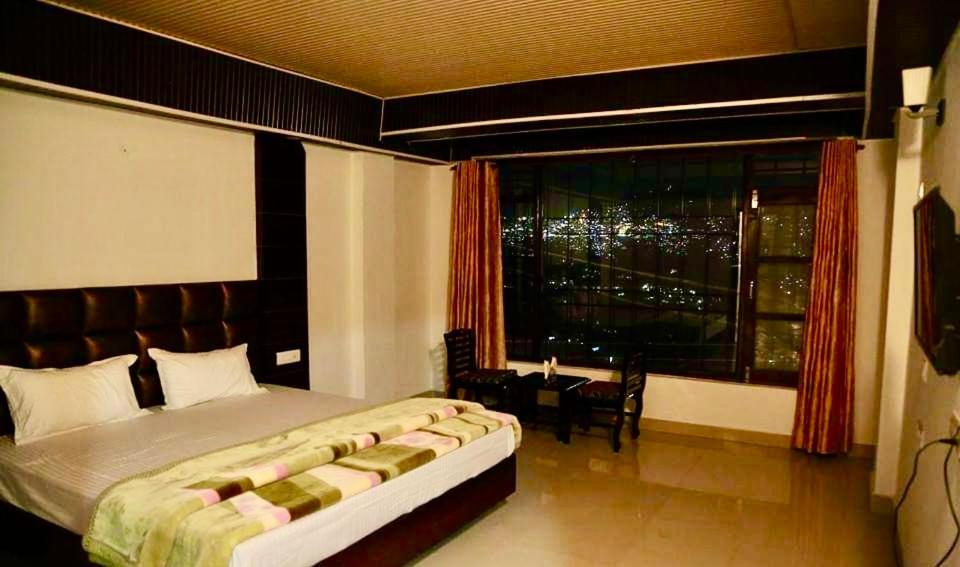 a bedroom with a large bed and a large window at Hotel SHIMLA REGENCY CHAKKAR in Shimla