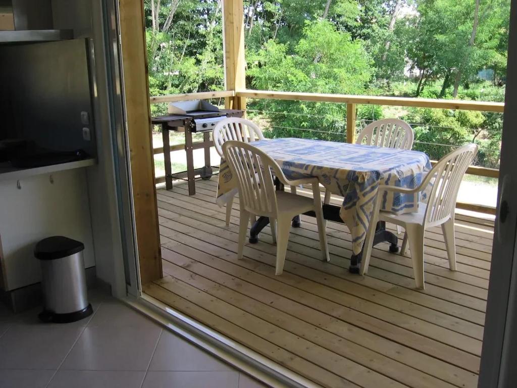 レ・マトゥにあるMaison familiale à Les Mathes avec jardin et saunaのポーチにテーブルと椅子、テーブルとテレビ