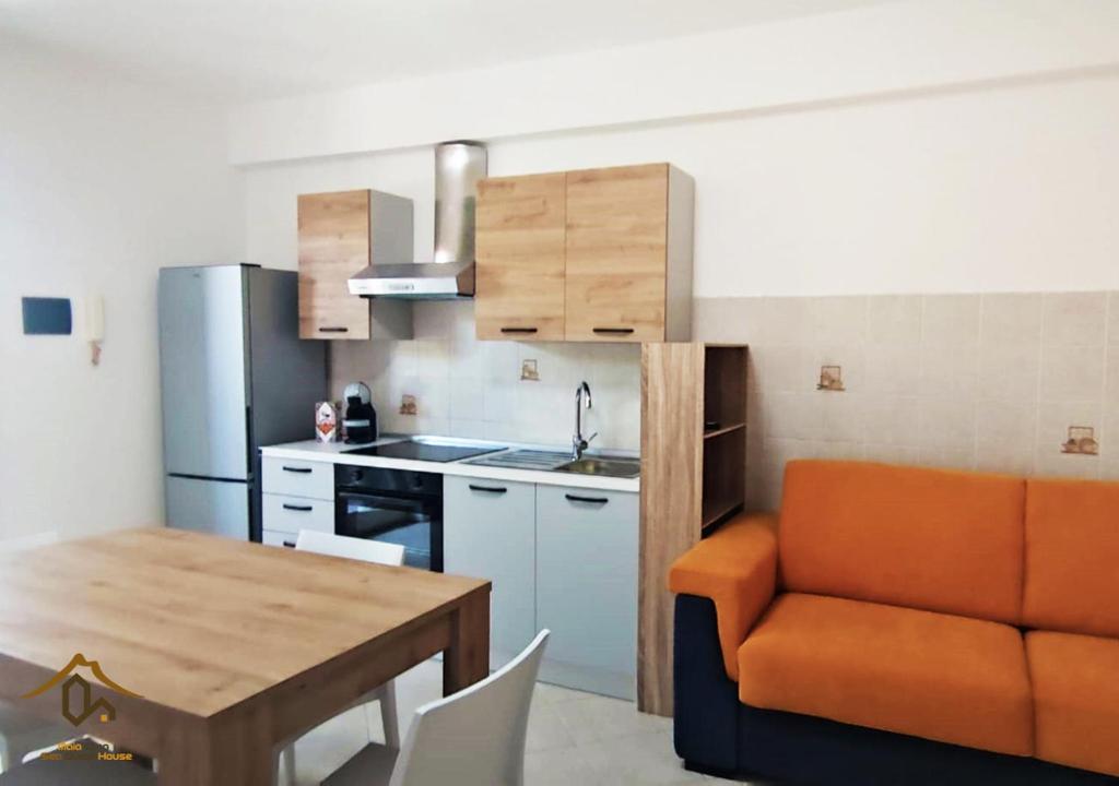 a kitchen with an orange couch and a table at Maia Etna Sea Guest House in Riposto
