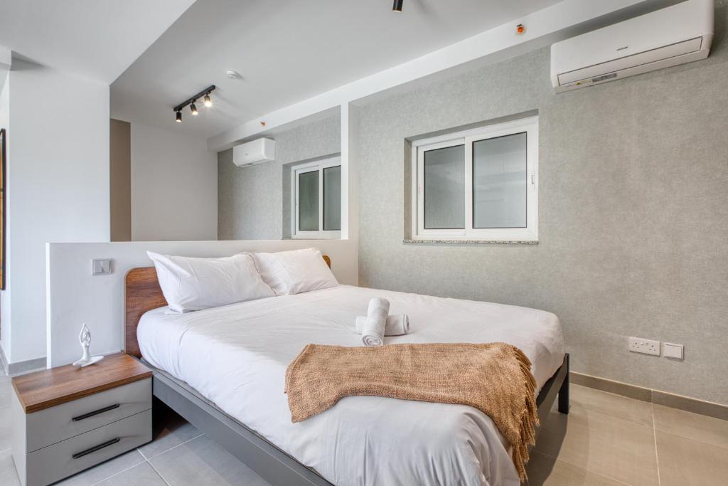 a bedroom with a large white bed and two windows at Luxury Apartment Heart of St Julians Sleeps 5 in San Pawl il Bahar