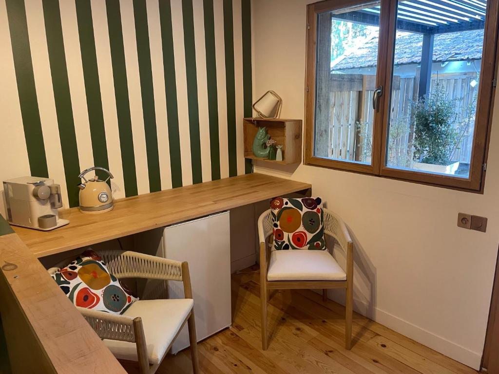 a room with a desk and two chairs and a window at Les ptis chiffons in Lacanau