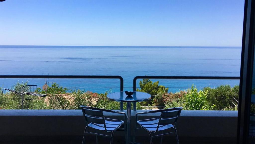 a table and two chairs on a balcony with the ocean at Casa Trama in Pisciotta
