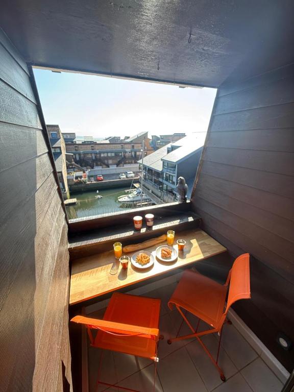 une table avec deux assiettes de nourriture et une fenêtre dans l'établissement Dans la Marina, charmant appartement, à Deauville