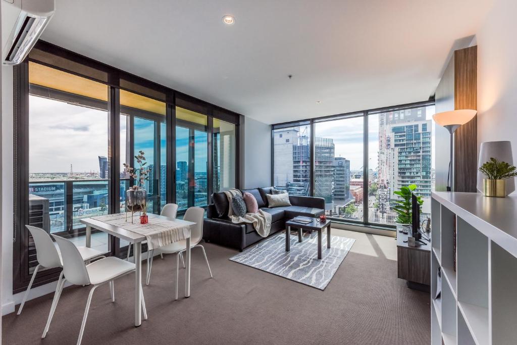 a living room with a table and chairs and windows at WOW Apartment on Spencer in Melbourne