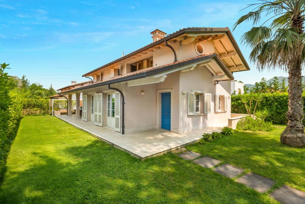 ein Haus mit einer Palme im Hof in der Unterkunft GOLDEN LUXE - Villa Golden next Twiga Beach Club in Marina di Pietrasanta