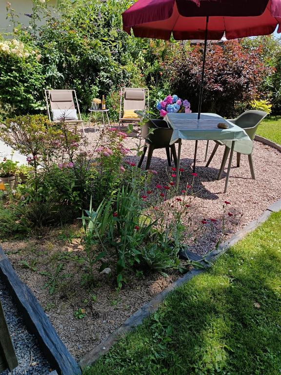 - un jardin avec une table, un parasol et des fleurs dans l'établissement Le Cottage de l'Albâtre Gîte 2 pers jardin parking à Vattetot sur Mer, à Vattetot-sur-Mer