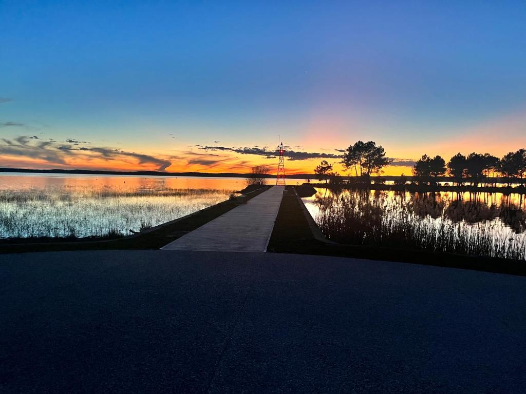 un coucher de soleil sur une masse d'eau avec un chemin dans l'établissement La parenthèse au pied du lac, à Lacanau