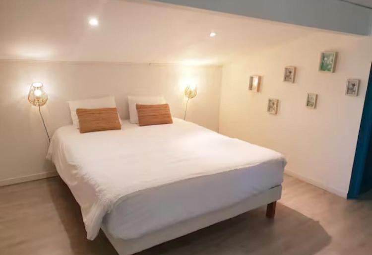 a bedroom with a large white bed with two pillows at Location Bassin Arcachon in Le Teich