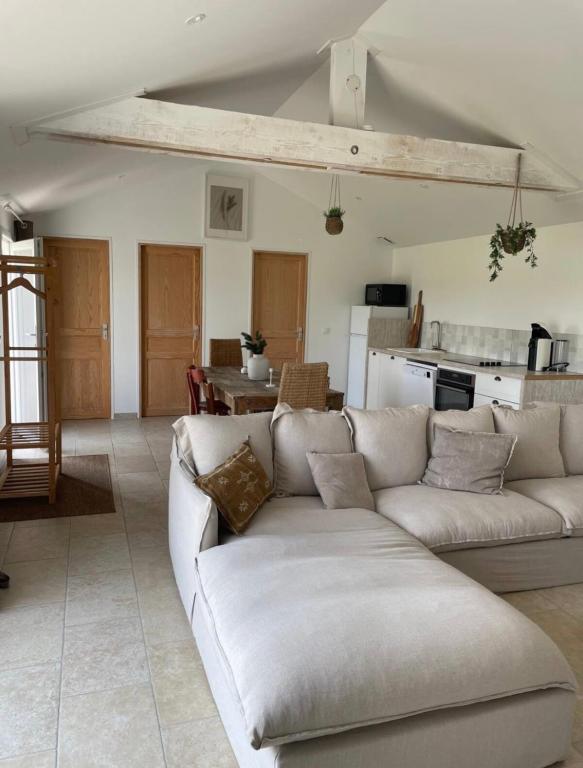 un salon avec un canapé et une cuisine dans l'établissement Longère cosy, à Saint-Maurice-lʼExil