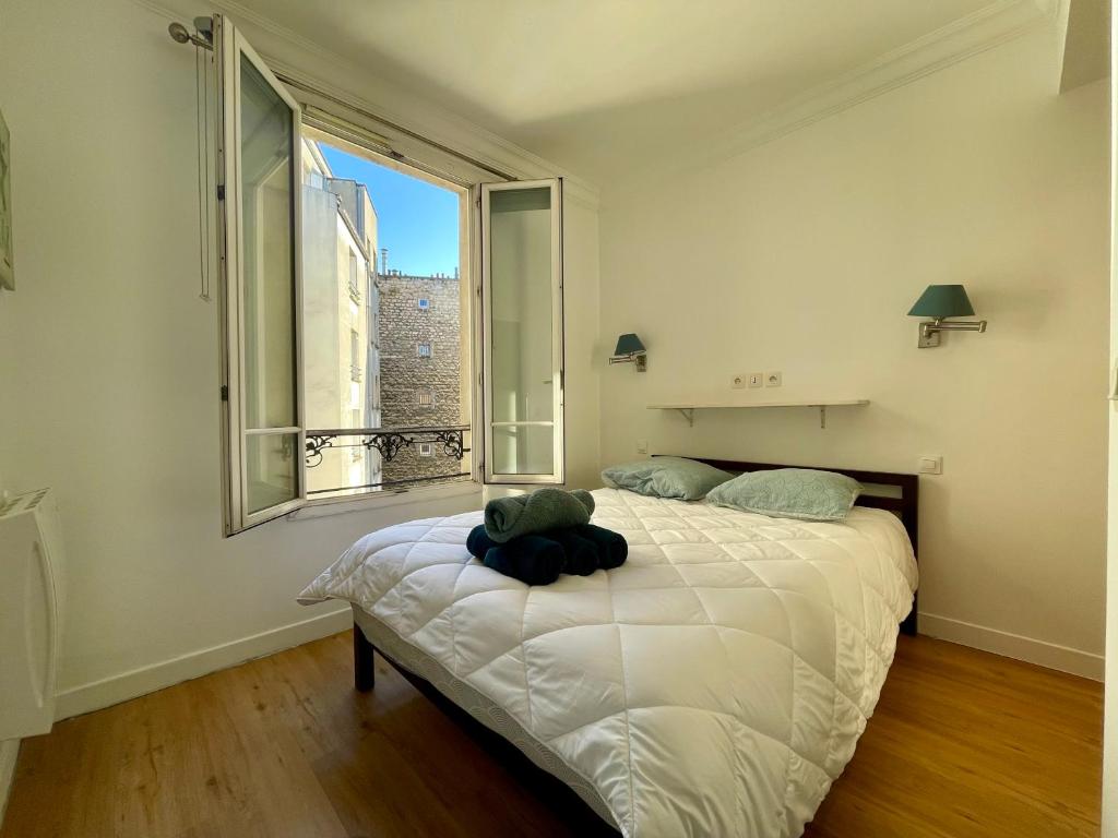 une chambre avec un grand lit avec une grande fenêtre dans l'établissement Appartement Tour Eiffel Maison de la Radio, à Paris