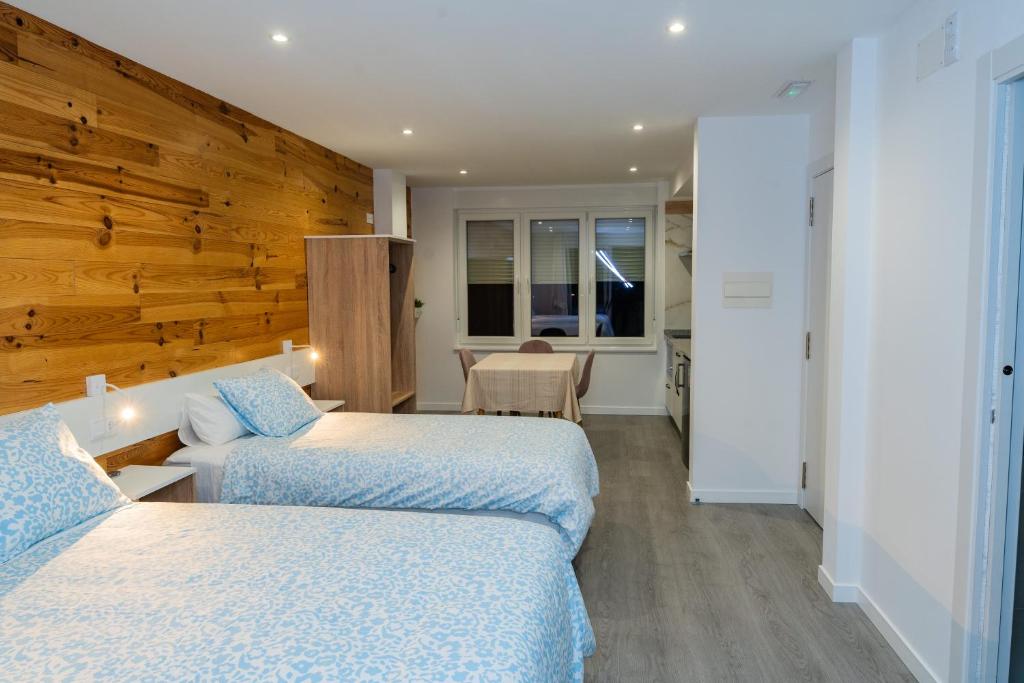 two beds in a room with a wooden wall at Pousadas CAMINO de FINISTERRE in Mazaricos