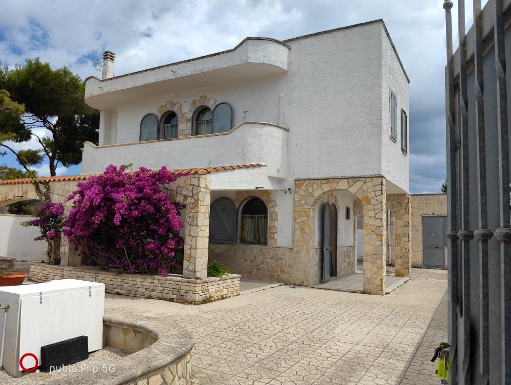 a white house with purple flowers in front of it at La casa delle isole in Torre Chianca