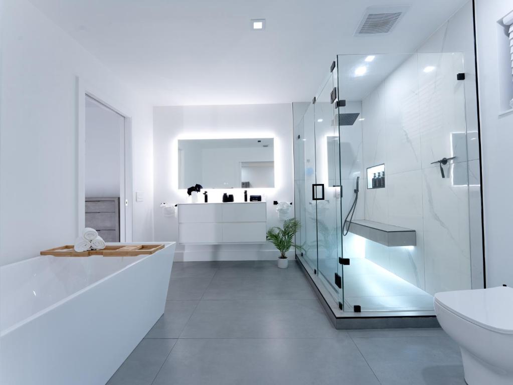 Un baño blanco con ducha de cristal y lavabo. en Casa Madrisqui, en Homestead