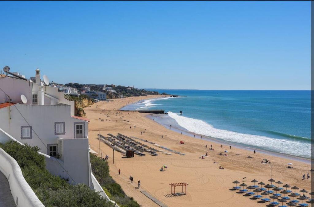 a beach with chairs and people on the sand and the ocean at Bayview Old Town Beach Apartment in Albufeira