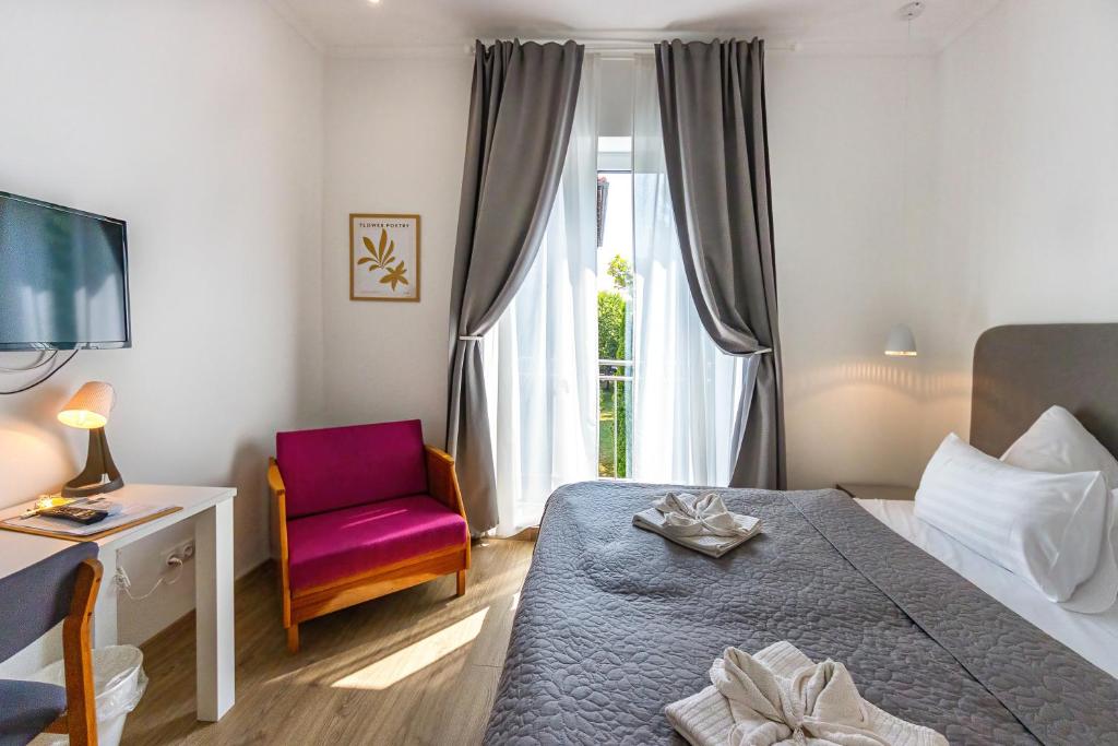 a bedroom with a bed and a chair and a window at PLAGE-ON Panzió in Siófok