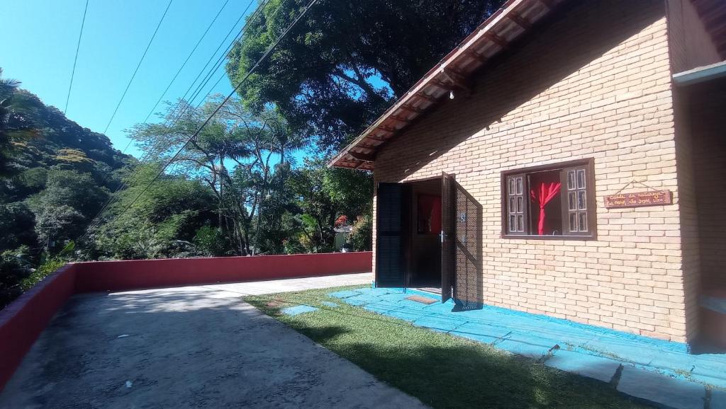 un edificio de ladrillo con puerta y ventana en Tahoma Chale Rustico côr Café e vermelho Prumirim Paraiso, en Ubatuba