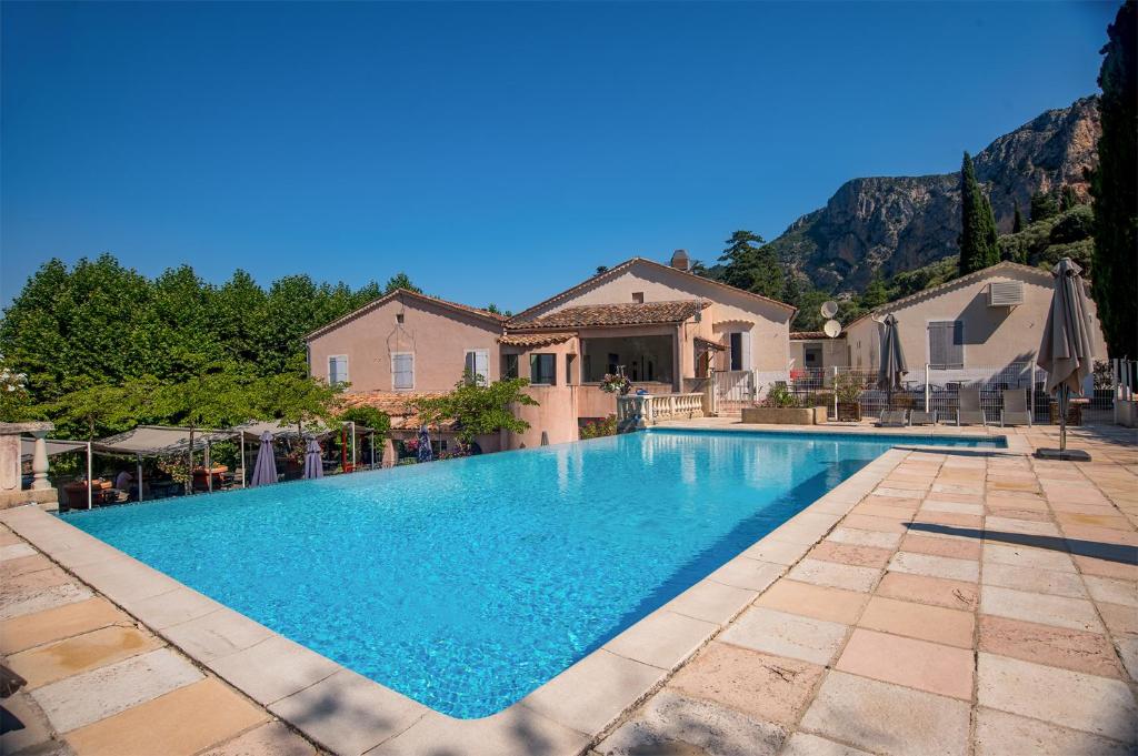 a large swimming pool in front of a house at Hôtel La Bonne Auberge in Moustiers-Sainte-Marie