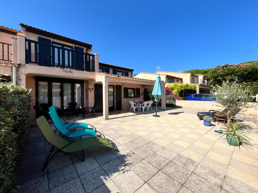 Cette maison dispose d'une terrasse avec des chaises et un parasol. dans l'établissement Domaine de vacances TAMARIS, à 600m de la plage, villa 3 chambres et séjour clic clac, wifi, cuisine climatisée, 7 couchages animations et piscines en supplément - LRTAMS10, à Portiragnes