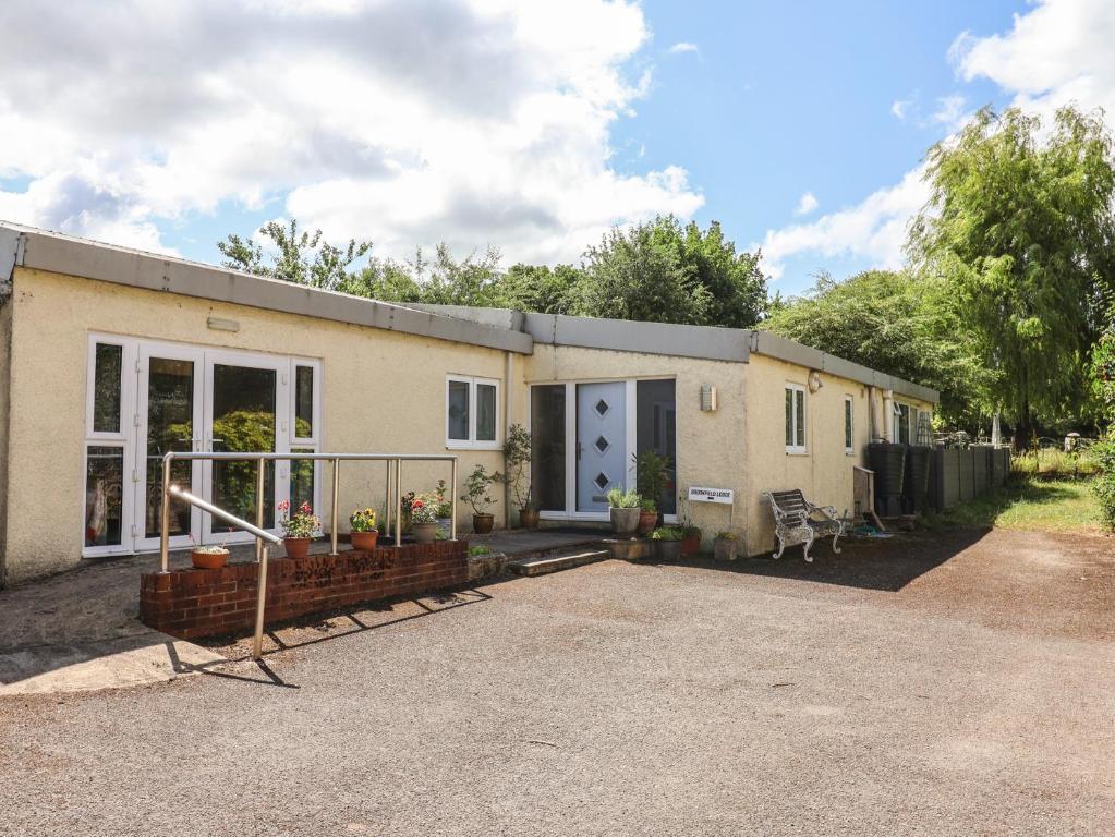 ein Haus mit einer Auffahrt davor in der Unterkunft Brookfield Lodge in Burstock