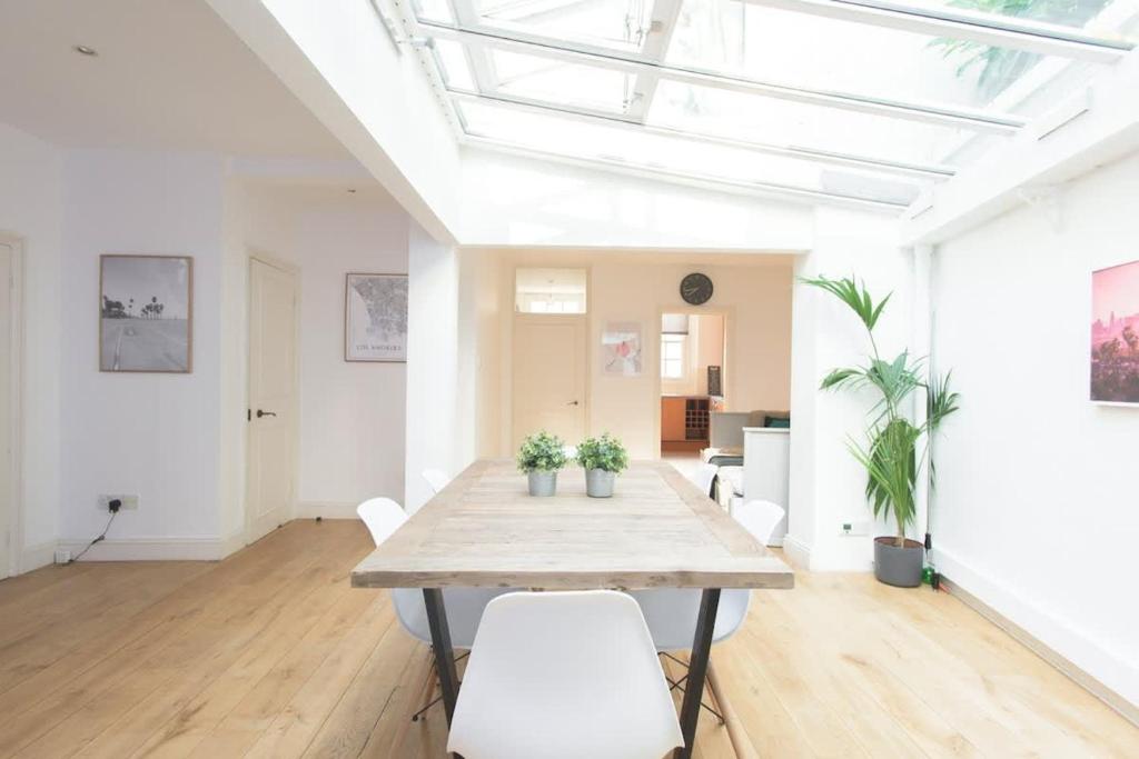 a dining room with a table and white chairs at The Harrods Mews - Modern 4BDR with Rooftop Terrace in London