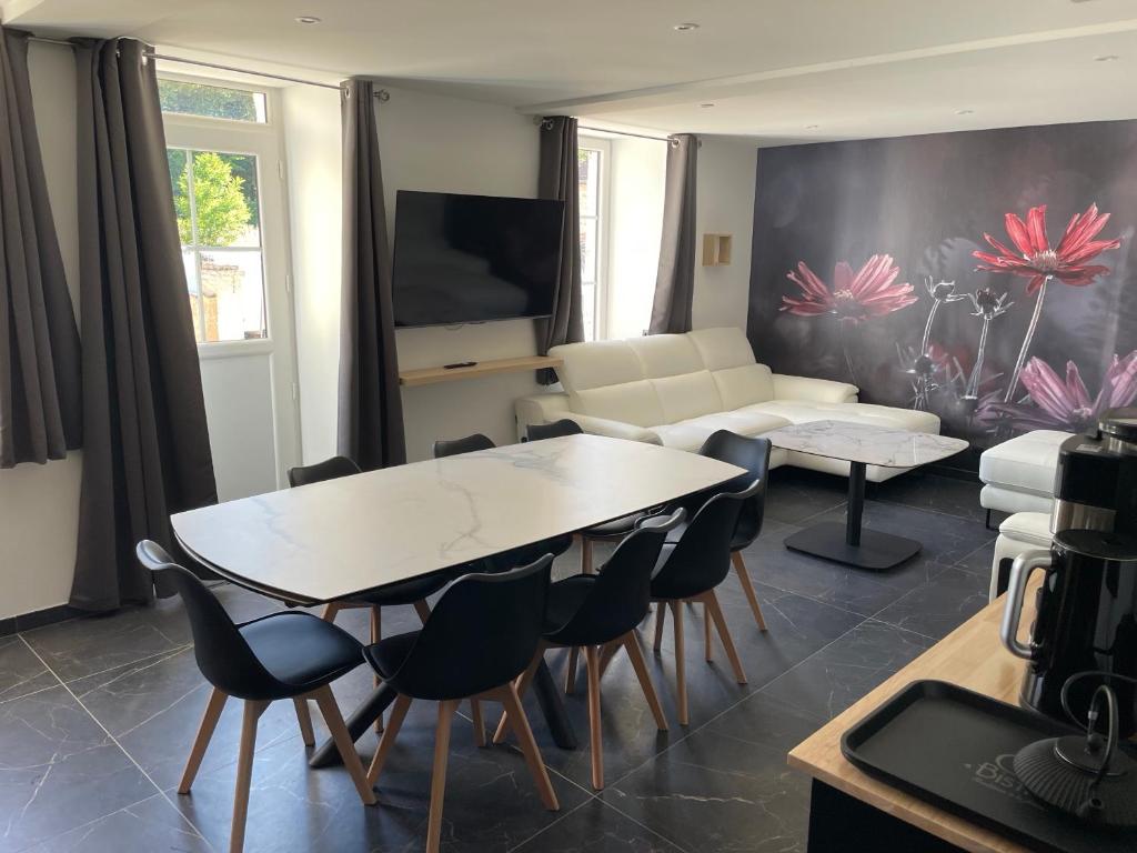 Una sala de estar con una mesa y sillas y un sofá. en La Maison des Lacs et des Parcs, en Amance