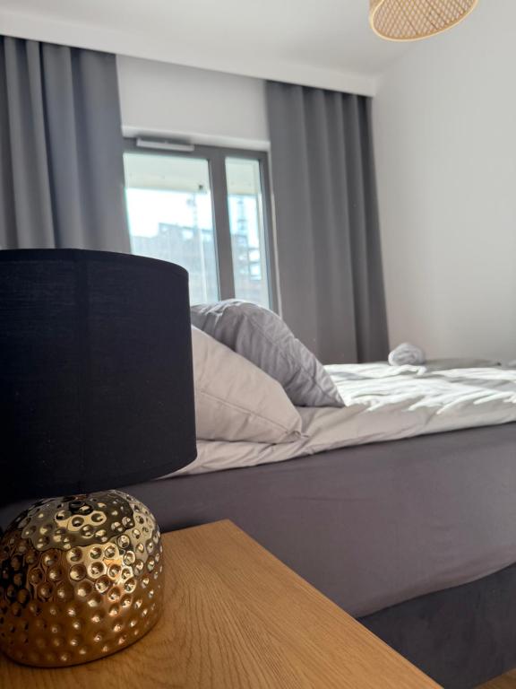 a bedroom with a bed and a table with a lamp at Apartament KTW3 in Katowice