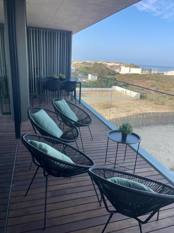 eine Terrasse mit Stühlen und Tischen und Blick auf den Strand in der Unterkunft LUX BeACH in Praia da Barra