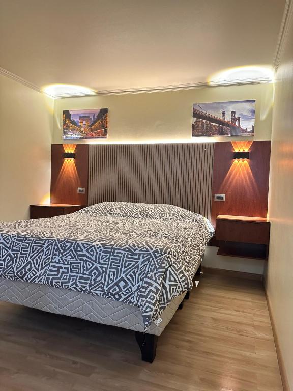 a bedroom with a bed with two lights on it at Departamento Calama in Calama