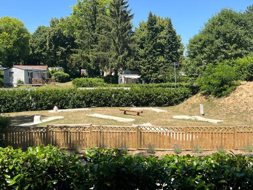 un parco con una staccionata di legno e una panchina di Mobil home tout confort a Saint-Chéron