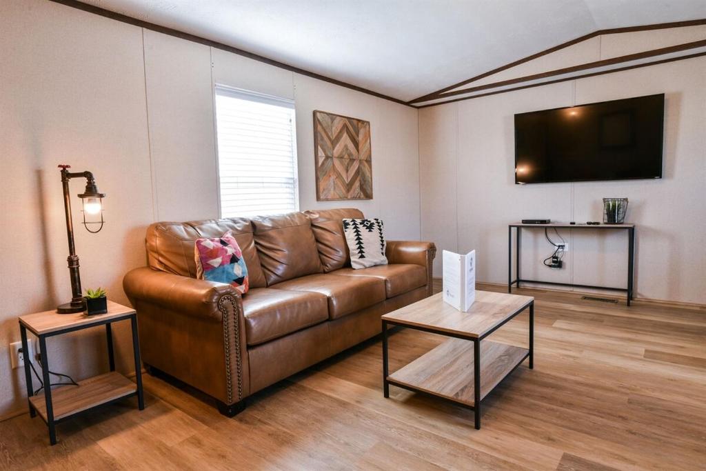 Il comprend un salon doté d'un canapé en cuir brun et d'une télévision à écran plat. dans l'établissement Special Rates -RedSandsHabitation 1-Moab-National Parks, à Moab