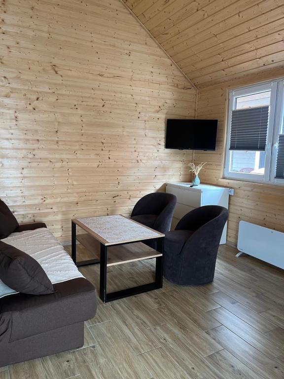 a living room with two couches and a tv at Zacisze Za Lasem in Jarosławiec