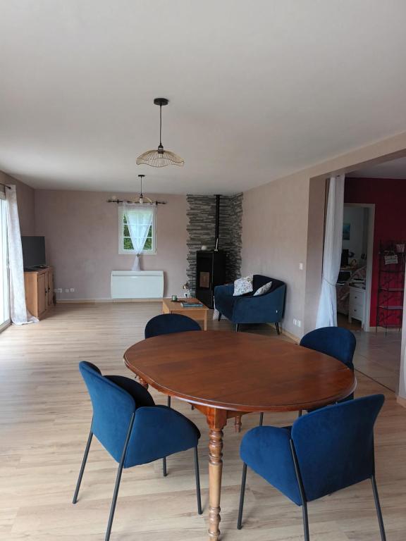 sala de estar con mesa de madera y sillas azules en Chambre campagne et salle de bain privée, en Le Mesnil-Guillaume