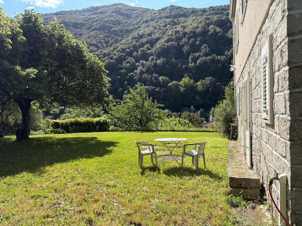 a table and bench in the grass next to a building at Appartement rez de jardin - Casa San Cesaru in Bains de Guitera