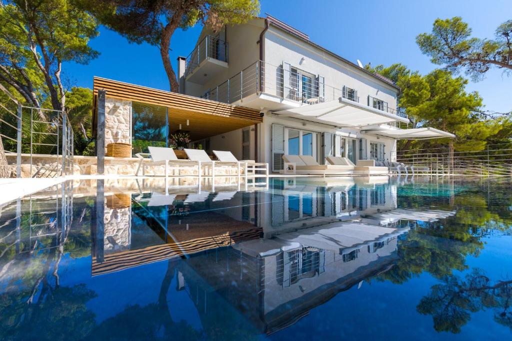 a house with a swimming pool in front of it at Magnificent Seafront Villa 10 Bedrooms Pakleni View Villa Private Infinity Pool & Amazing Sea Views Hvar Town in Hvar