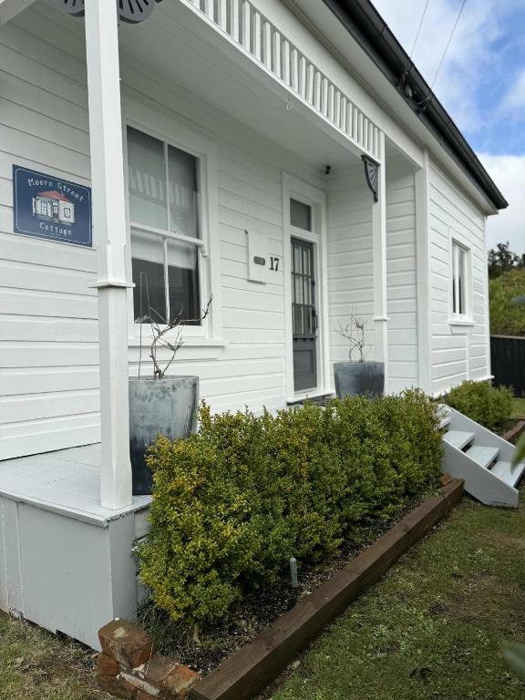 a white house with bushes in front of it at Moore St Cottage in Ohakune
