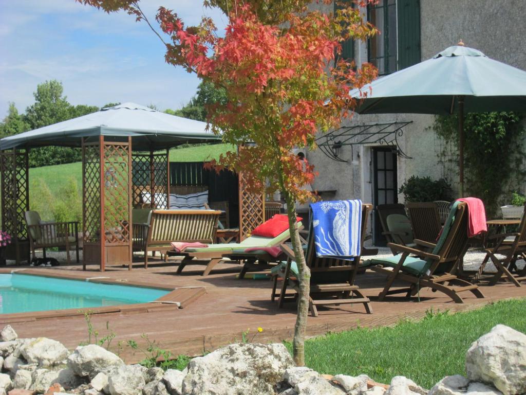 un patio avec des chaises et des parasols à côté d'une piscine dans l'établissement Le Petit Lavoir, à Saint-Paul-Lizonne