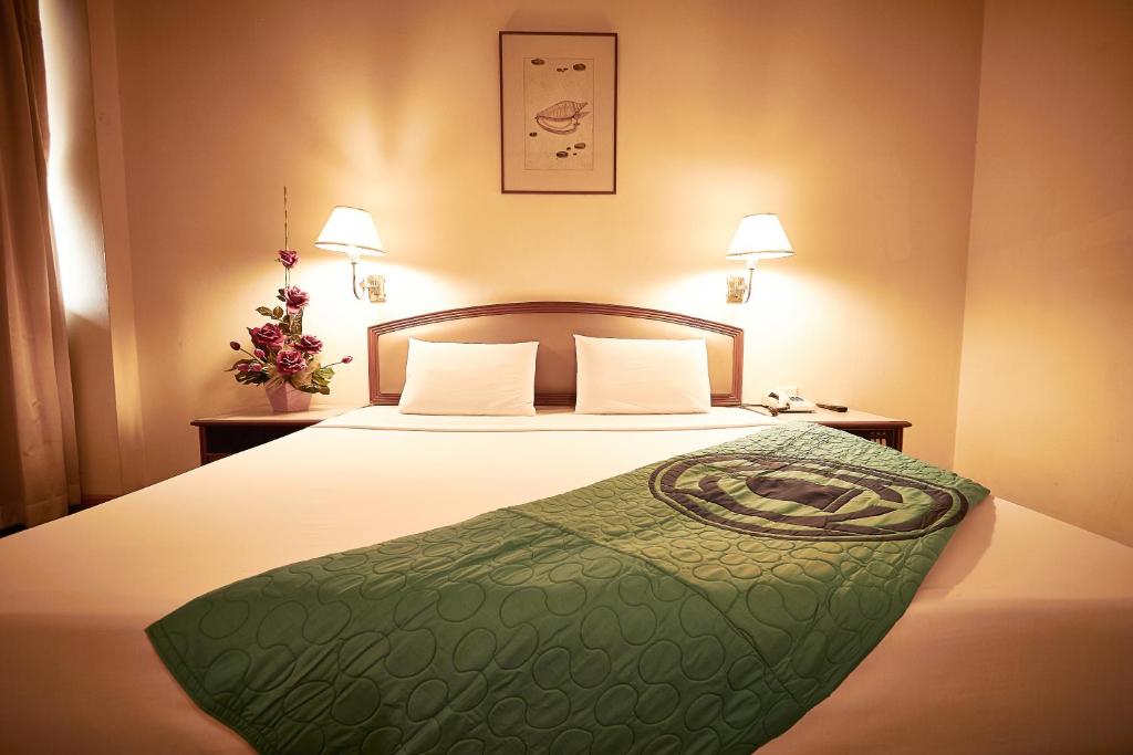a hotel room with a bed with a green comforter at Kosit Hotel in Hat Yai