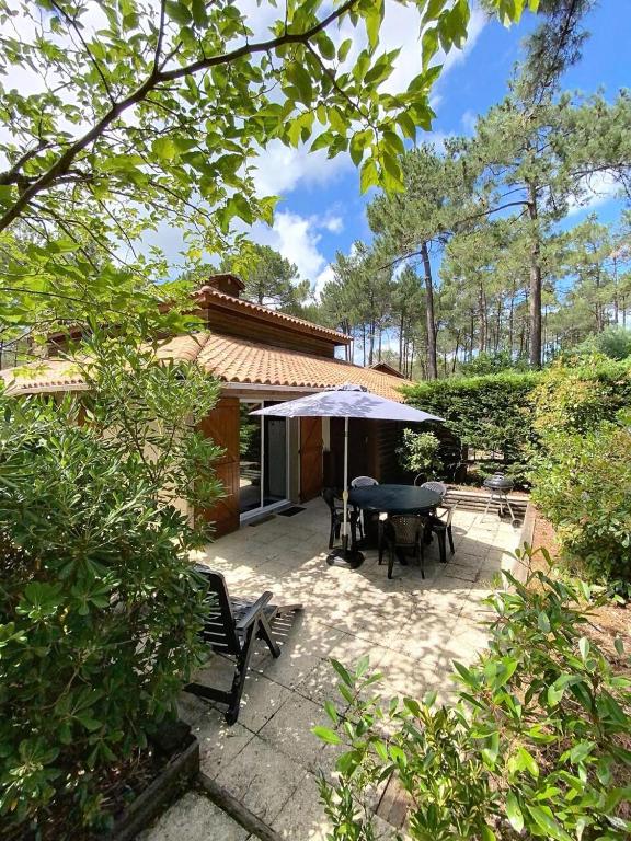 un patio avec une table et un parasol dans l'établissement Résidence Jardins De L'ocean - Pavillon mitoyen 1 chambre + mezzanine, 4 pers, résidence avec piscine MAE-0641, à Lacanau