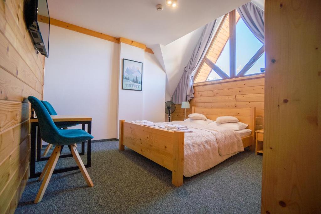 a bedroom with a bed and a chair and a window at Villa Kaplowa Chata & SPA in Zakopane