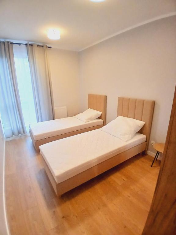 two beds in a room with wooden floors at Słoneczny Apartament in Kłodzko